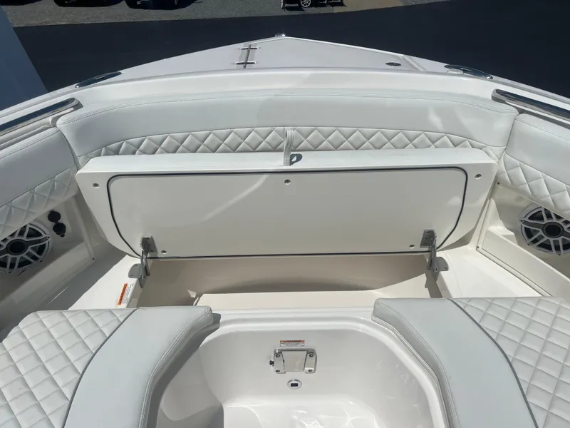 Slide: The Image of 2024 Pursuit DC 306 Dual Console boat interior with white quilted seating and storage compartment. - 29