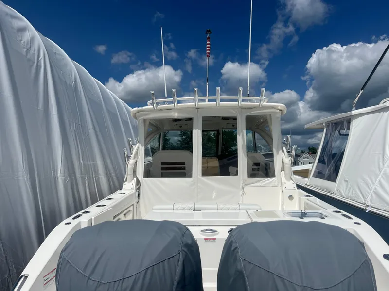 Slide: The Image of 2024 Pursuit DC 306 Dual Console boat docked under a blue sky with clouds. - 5