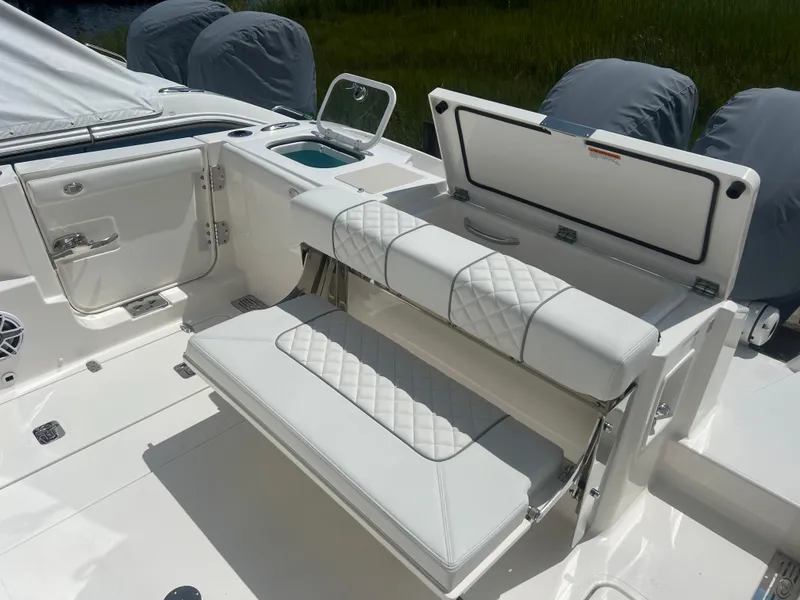 Slide: The Image of 2024 Pursuit DC 306 Dual Console boat interior with white cushioned seating and storage. - 7