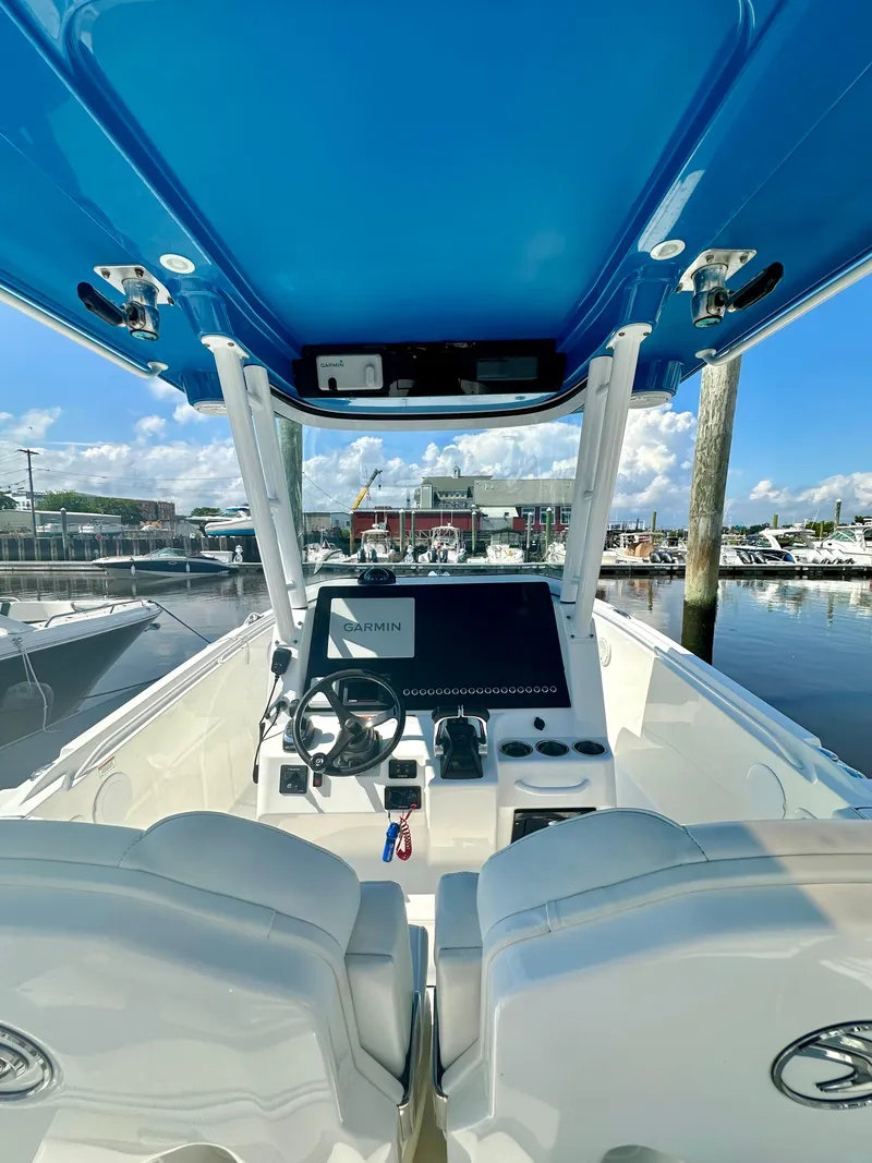 Slide: The Image of 2019 Edgewater 280CC boat interior with blue canopy, docked at marina. - 13