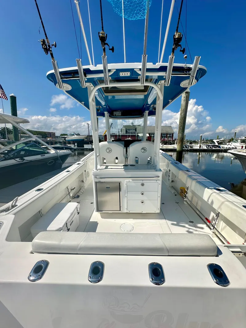 Slide: The Image of 2019 Edgewater 280CC boat with spacious deck and fishing rod holders at marina. - 14