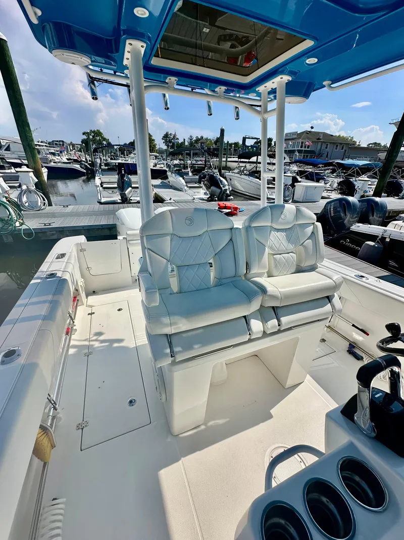 Slide: The Image of 2019 Edgewater 280CC boat interior with dual seats and blue canopy at marina. - 15