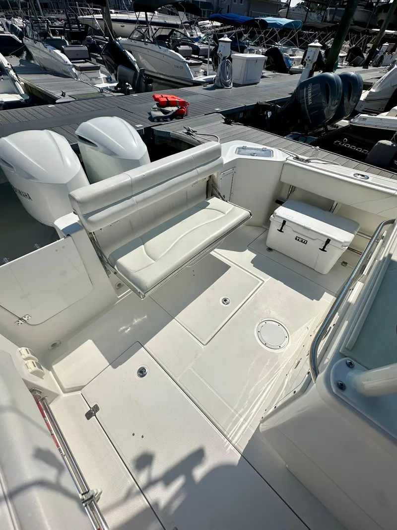 Slide: The Image of 2019 Edgewater 280CC boat interior with seating and storage at a marina. - 17