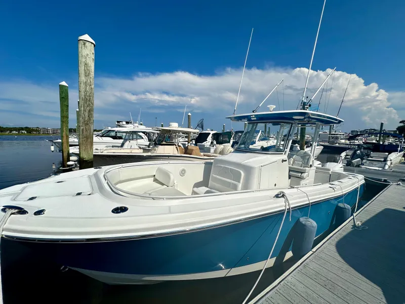 Slide: The Image of 2019 Edgewater 280CC boat docked at marina under clear blue sky. - 2