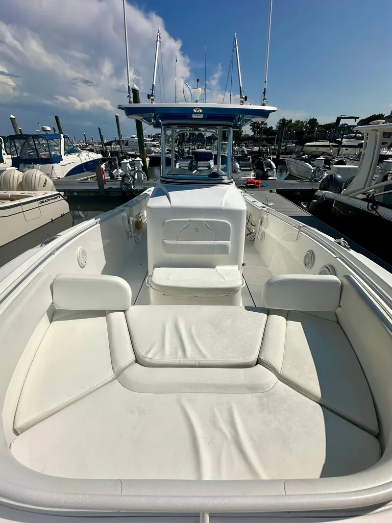 Slide: The Image of 2019 Edgewater 280CC boat with spacious seating, docked at a marina under a clear sky. - 4