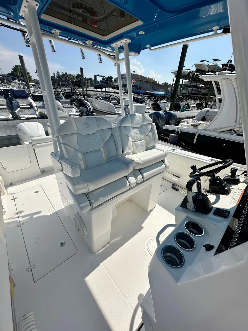 Slide: The Image of 2019 Edgewater 280CC boat interior with seating and control panel at marina. - 9