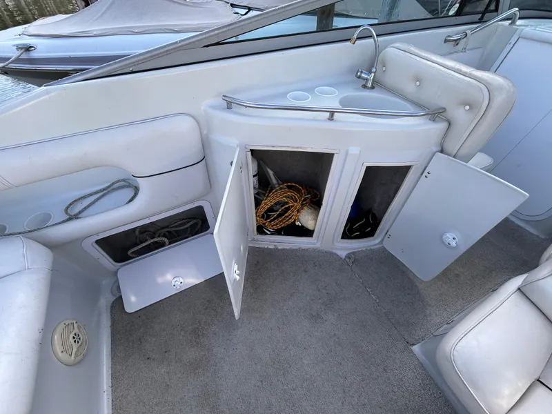 Slide: The Image of 2000 Crownline 266 CCR boat interior with open storage cabinets and sink. - 11