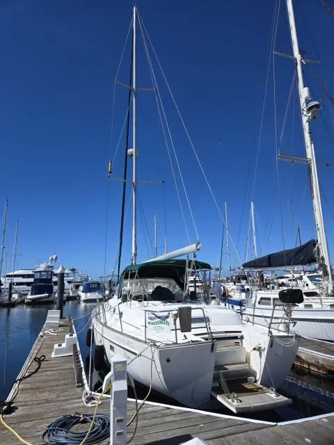 Slide: The Image of 2003 Beneteau 42CC Oceanis Clipper sailboat docked at marina under clear blue sky. - 42