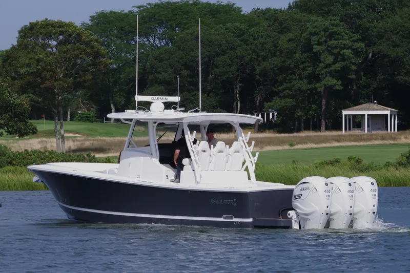 Slide: The Image of 2025 Regulator 37 boat cruising on a lake with lush greenery in the background. - 6