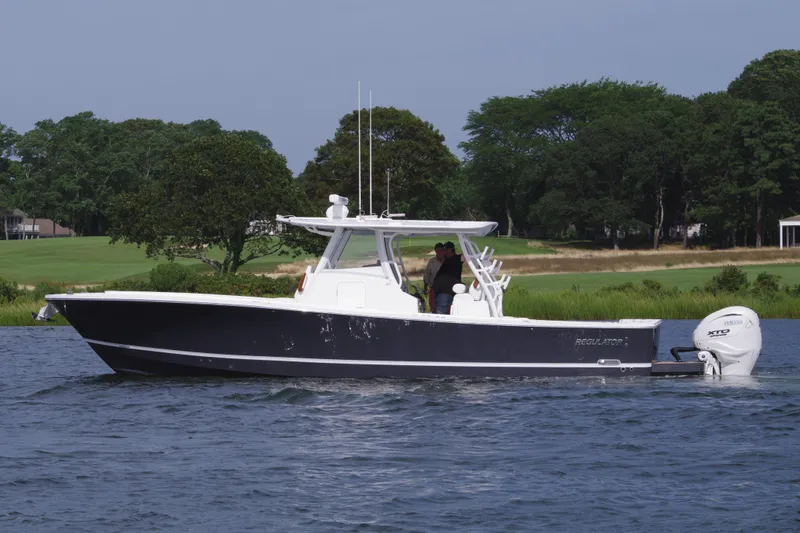 Slide: The Image of 2025 Regulator 37 boat cruising on a lake with lush green trees in the background. - 7