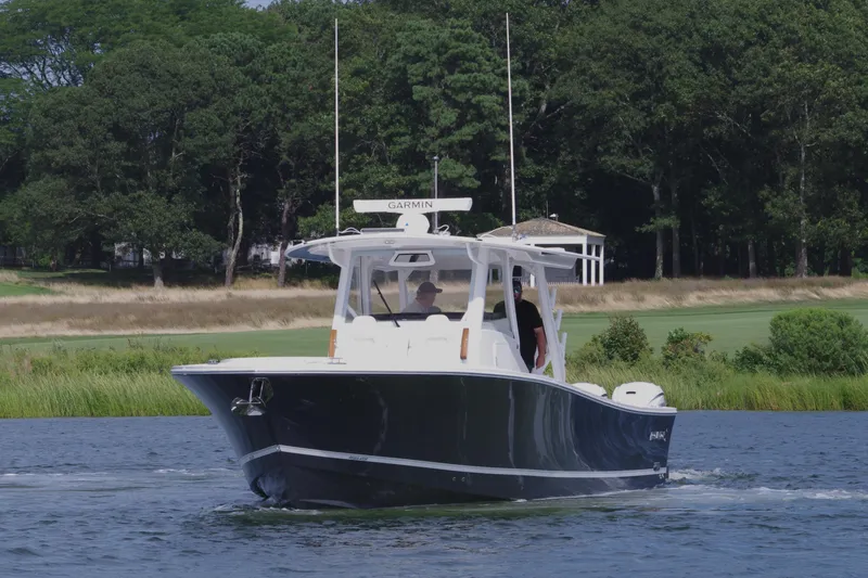 Slide: The Image of 2025 Regulator 37 boat cruising on a calm lake with lush greenery. - 9