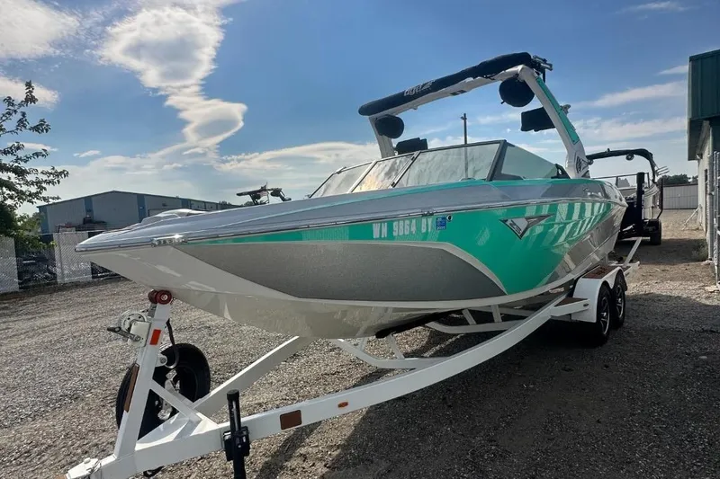 Slide: The Image of 2022 Tigé Z3 boat on trailer, teal and white design, parked outdoors. - 14