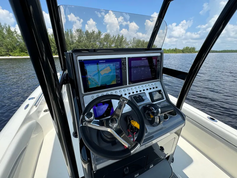 Slide: The Image of 2022 ShearWater 270 Carolina Flare boat dashboard with navigation screens and steering wheel. - 12