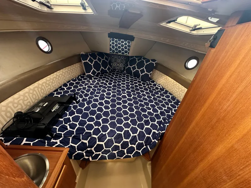 Slide: The Image of 2019 Ranger Tugs R-23 cabin interior with blue geometric bedding and wooden finishes. - 22