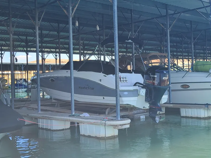 Slide: The Image of 2021 NauticStar 243 DC boat docked in a covered marina. - 6