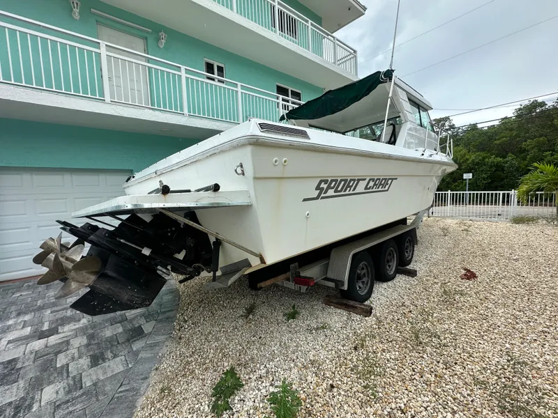 Slide: The Image of 1996 Sport-Craft 272 Sportfish boat on trailer, parked near a turquoise building. - 2