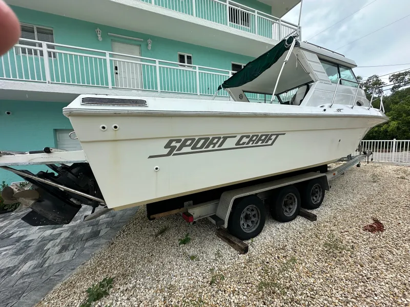 Slide: The Image of 1996 Sport-Craft 272 Sportfish boat on trailer, parked near a turquoise building. - 3