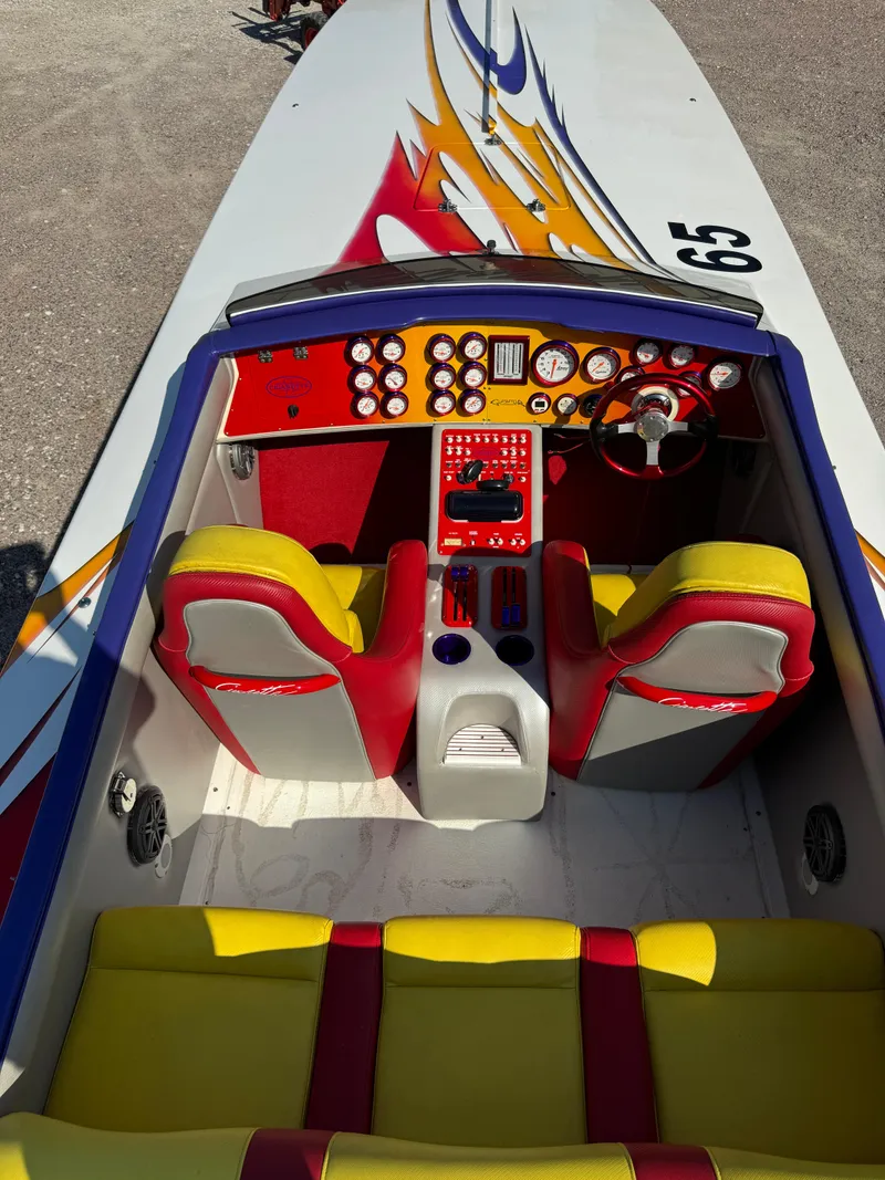 Slide: The Image of 2002 Cigarette 36 Gladiator boat interior with vibrant red and yellow seating, detailed dashboard. - 20