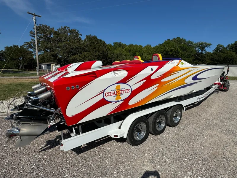 Slide: The Image of 2002 Cigarette 36 Gladiator speedboat with vibrant red, orange, and white design on a trailer. - 6