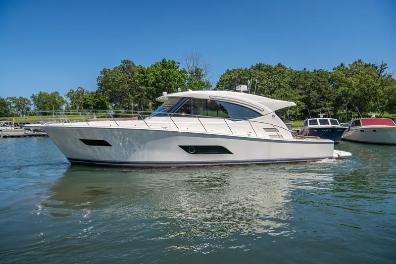 The Image of 2020 Riviera 525 SUV yacht cruising on a sunny day in a serene marina. - 1