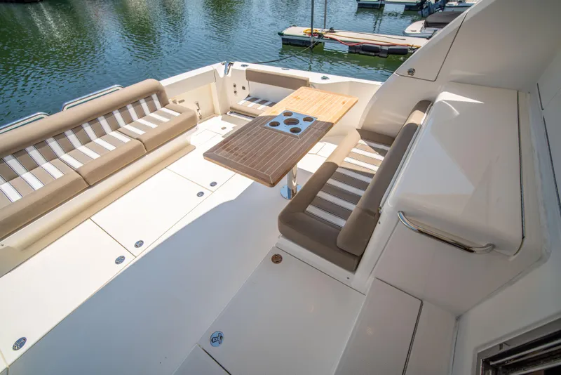 Slide: The Image of 2020 Riviera 525 SUV yacht deck with seating and table, docked by the water. - 14