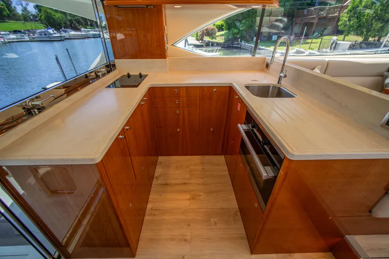 Slide: The Image of Luxurious 2020 Riviera 525 SUV yacht kitchen with modern wood cabinetry and waterfront view. - 25