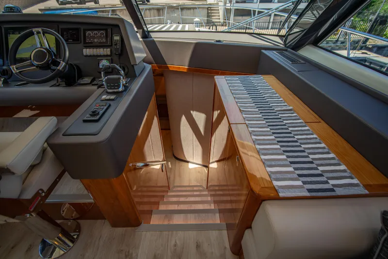 Slide: The Image of Interior of 2020 Riviera 525 SUV yacht, featuring helm and wooden staircase. - 29