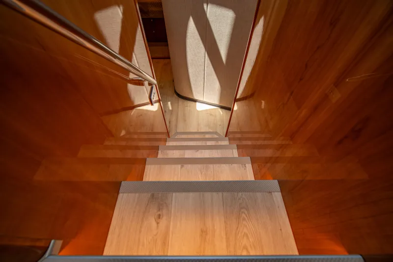 Slide: The Image of Wooden staircase inside 2020 Riviera 525 SUV yacht, featuring sleek design and warm lighting. - 32