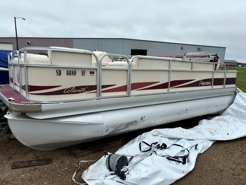 Slide: The Image of 1996 Premier ALANTE pontoon boat with maroon accents, parked outdoors. - 11