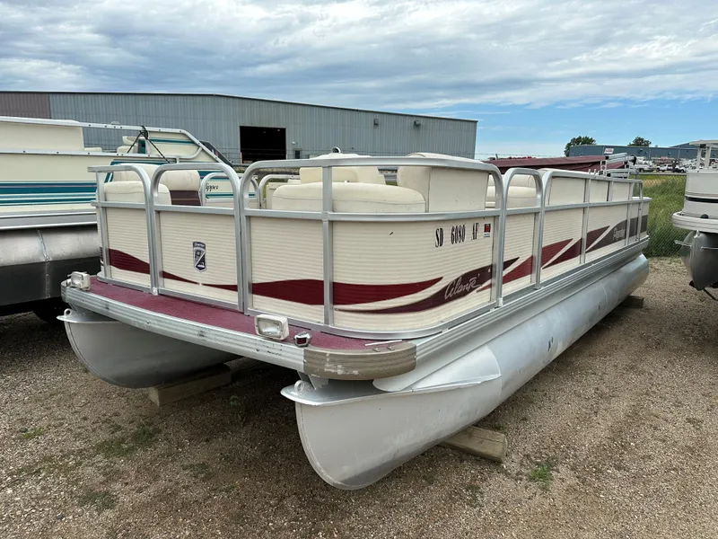 Slide: The Image of 1996 Premier ALANTE pontoon boat with red accents, parked outdoors near a warehouse. - 7