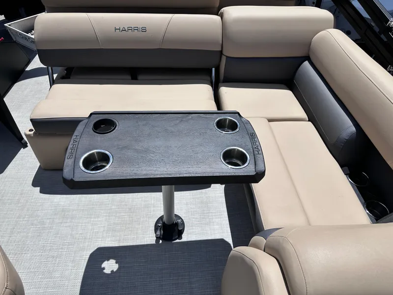 Slide: The Image of 2023 Harris Cruiser 230 interior with beige seating and a black table featuring cup holders. - 19