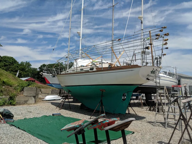 Slide: The Image of 1984 Cape Dory Cutter sailboat on dry dock, ready for maintenance under a clear sky. - 0