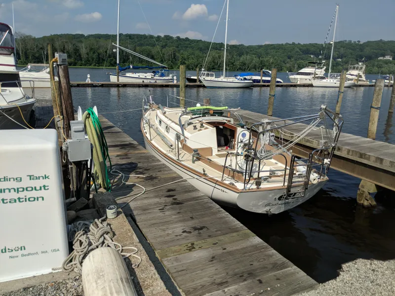 Slide: The Image of 1984 Cape Dory Cutter sailboat docked at a marina with scenic background. - 2