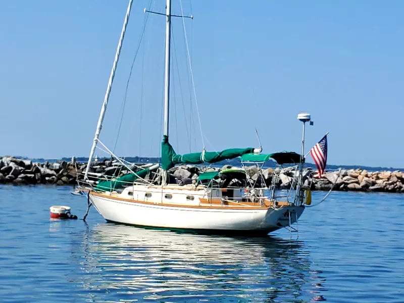 Slide: The Image of 1984 Cape Dory Cutter sailboat anchored in calm waters with American flag. - 3