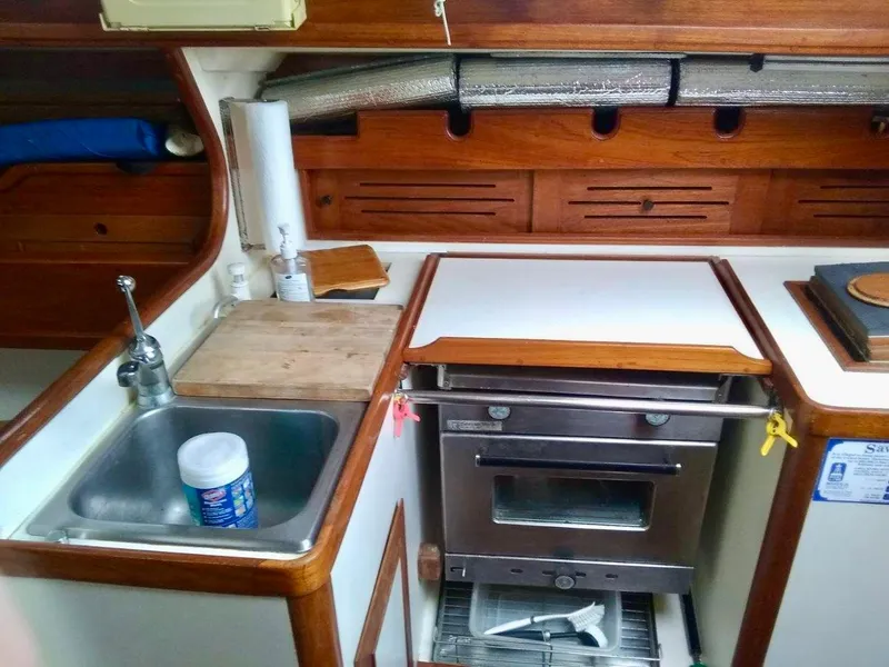 Slide: The Image of 1984 Cape Dory Cutter kitchen with sink, stove, and wooden cabinetry. - 8