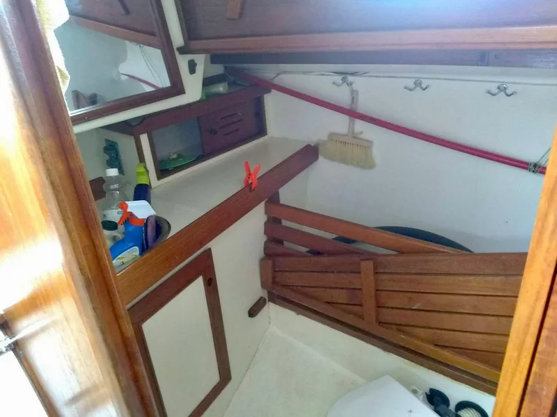 Slide: The Image of 1984 Cape Dory Cutter interior with wooden storage and cleaning supplies. - 9