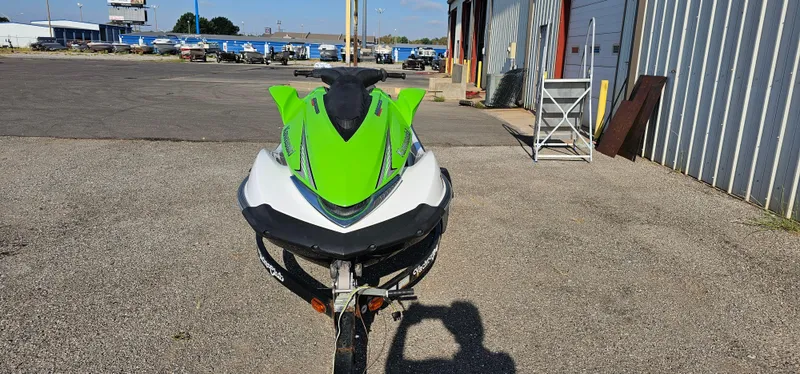 Slide: The Image of 2008 Kawasaki ULTRA250X jet ski, green and white, parked on asphalt near industrial buildings. - 2