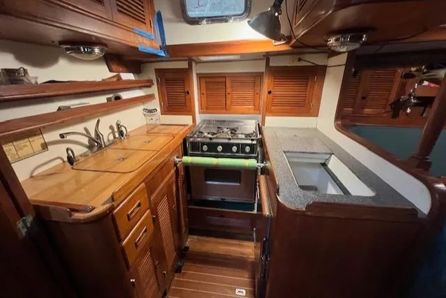 Slide: The Image of 1984 Mason 43 Cutter yacht kitchen with wooden cabinetry and compact stove. - 12