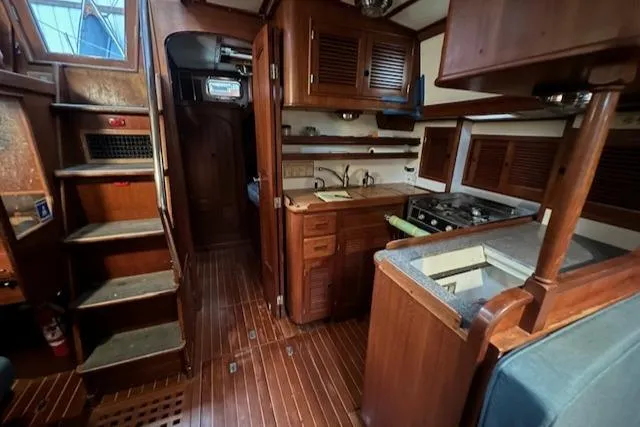 Slide: The Image of Interior of a 1984 Mason 43 Cutter sailboat with wooden cabinetry and compact kitchen. - 14
