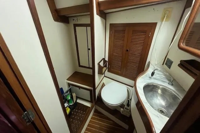 Slide: The Image of Compact bathroom in a 1984 Mason 43 Cutter sailboat with wooden accents and a stainless steel sink. - 28