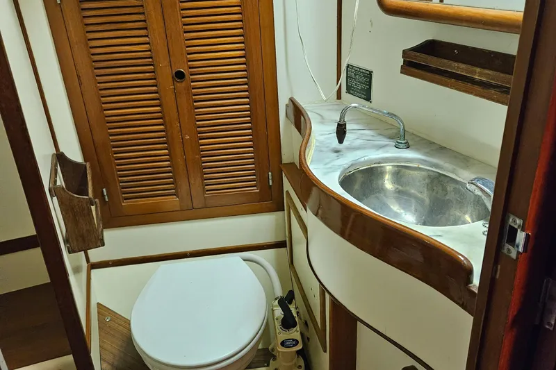 Slide: The Image of 1984 Mason 43 Cutter yacht bathroom with sink, toilet, and wooden cabinetry. - 29
