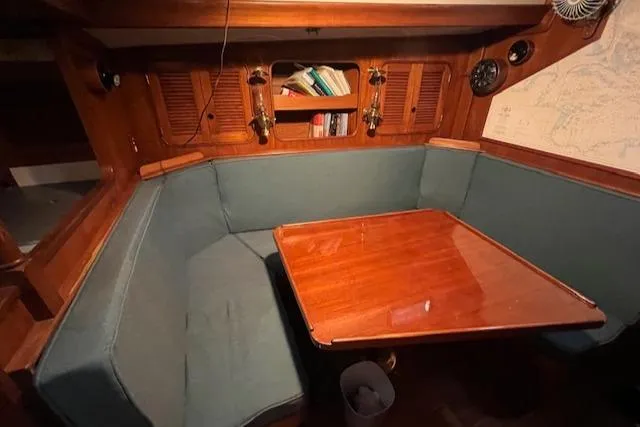 Slide: The Image of Cozy dining area in 1984 Mason 43 Cutter sailboat with wooden table and cushioned seating. - 3