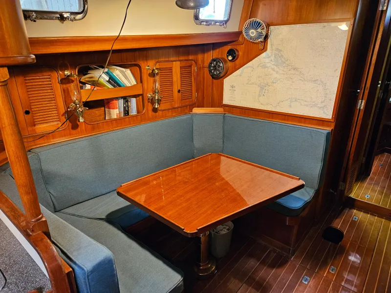 Slide: The Image of Cozy 1984 Mason 43 Cutter sailboat interior with wooden table and blue seating. - 4