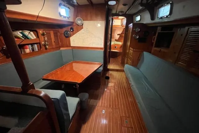 Slide: The Image of Interior of 1984 Mason 43 Cutter sailboat with wood paneling and cozy seating area. - 5