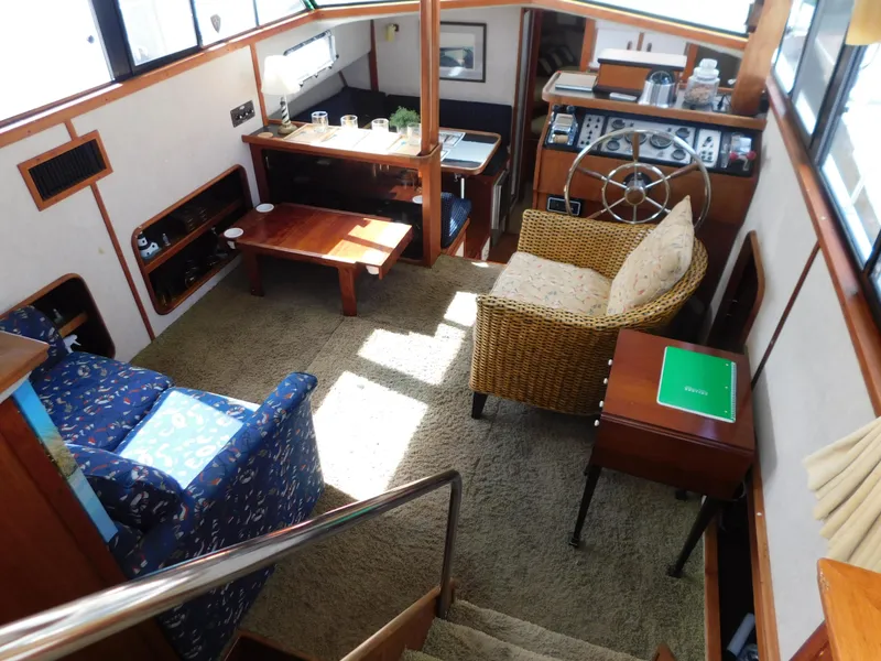 Slide: The Image of 1985 Carver 3607 Aft Cabin interior with cozy seating, helm, and wooden accents. - 13