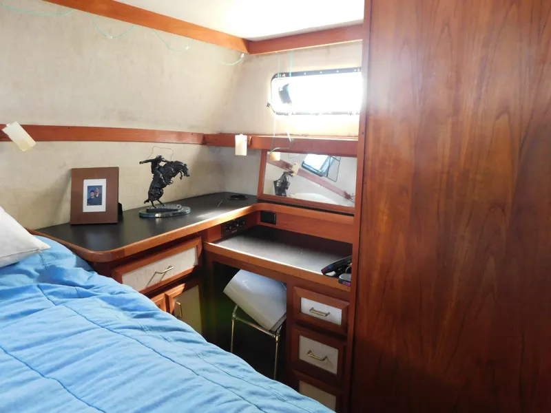 Slide: The Image of 1985 Carver 3607 Aft Cabin interior with wooden cabinetry, desk, and blue bedding. - 27