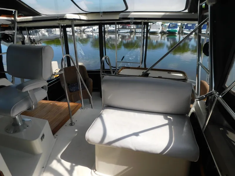 Slide: The Image of 1985 Carver 3607 Aft Cabin interior with seating, overlooking marina. - 10