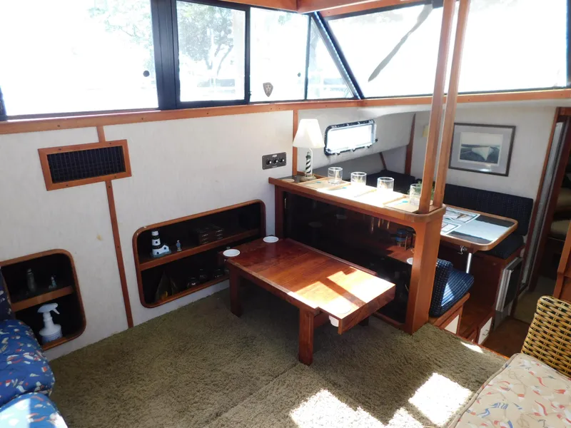 Slide: The Image of 1985 Carver 3607 Aft Cabin interior with dining area, wooden table, and natural light. - 14