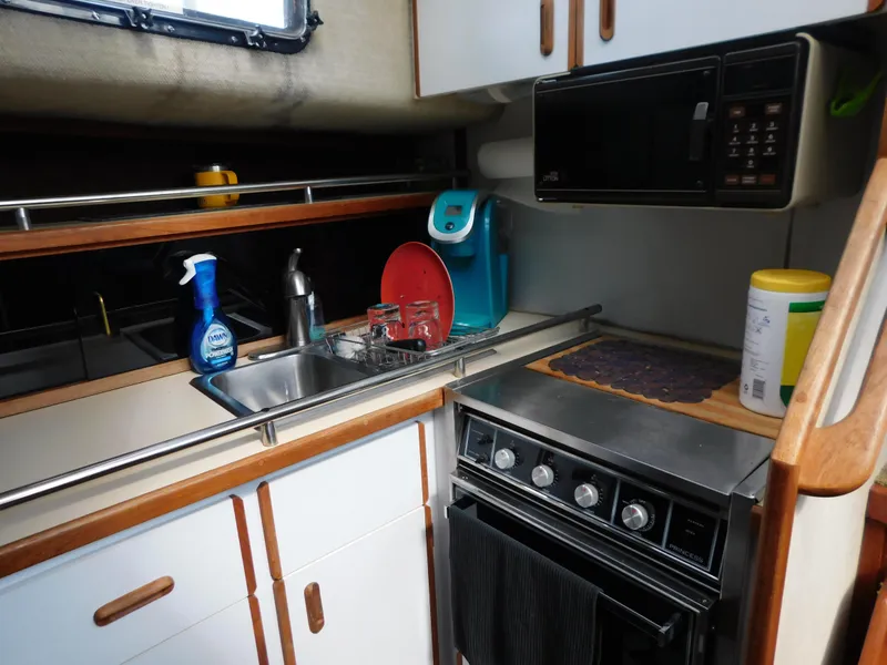 Slide: The Image of 1985 Carver 3607 Aft Cabin kitchen with sink, stove, and microwave. - 18