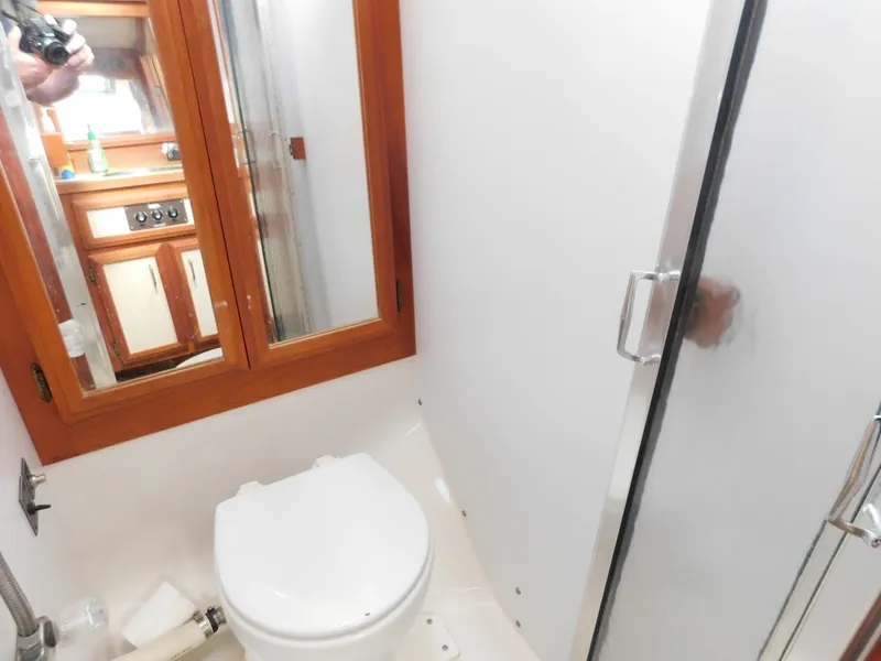 Slide: The Image of 1985 Carver 3607 Aft Cabin bathroom with toilet, shower, and wooden cabinetry. - 21